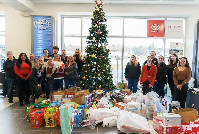Steet Ponte Nissan Employees around a Christmas tree with presents