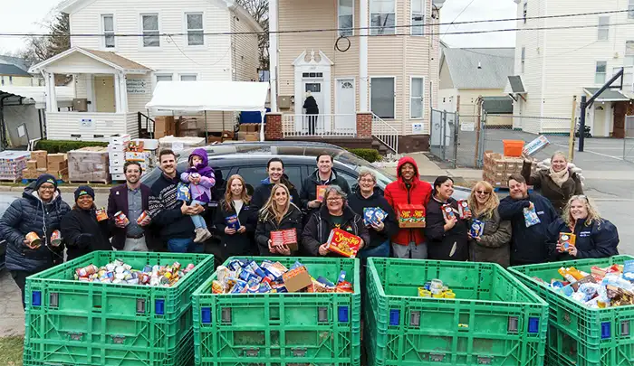 Steet Ponte Nissan Employees outside holding food donations in front of crates with food in them